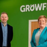 Man and woman standing in front of a green wall and Growflo logo.