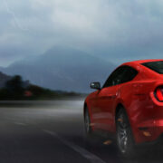 Red sport car drive on mountain highway in storm night.