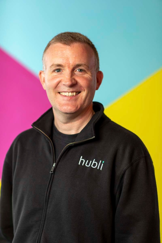 Smiling man in front of colourful wall.