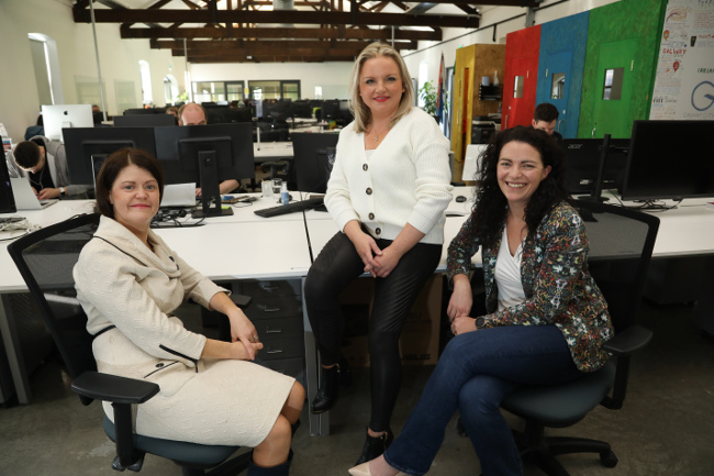 Three women sitting at a desk.