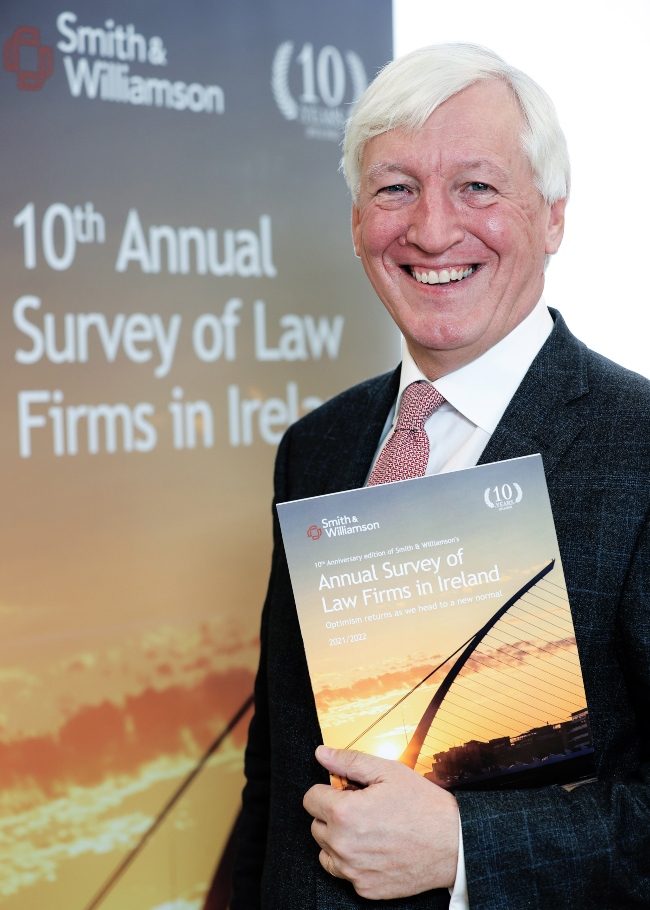 Smiling man in suit holding a report.