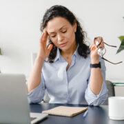 middle-aged businesswoman feeling headache on workplace, suffering from migraine or menopause.