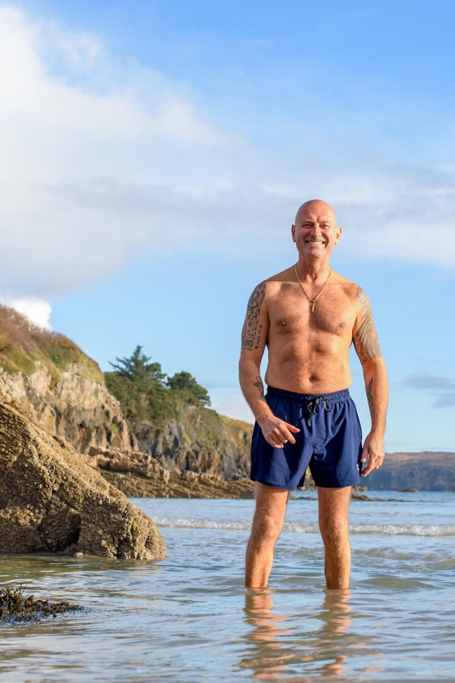 Man wearing swimming shorts by the sea.