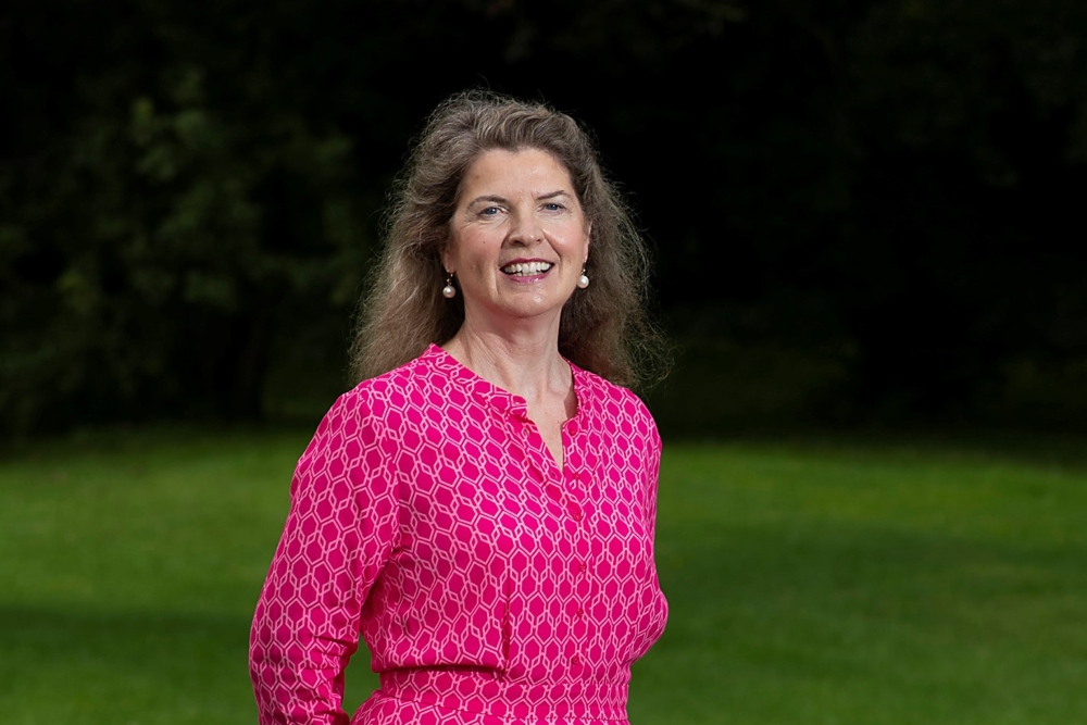 Woman in pink dress standing in a garden.