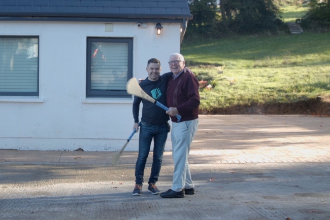 Man and son holding hurley sticks.