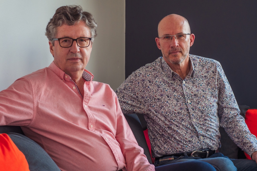 Two men in pink and blue shirts.