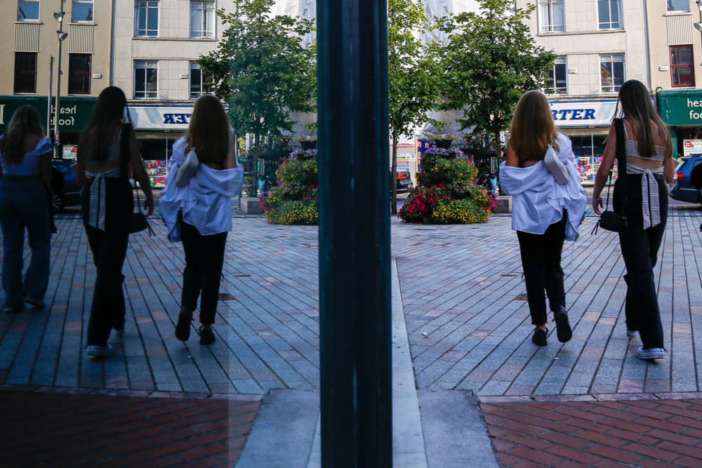 People walking in front of a display window in Cork City.