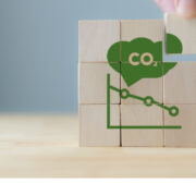 Hand puts the wooden cubes with CO2 emission reduction icon.