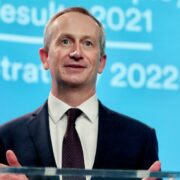 Man in suit speaking on podium.