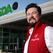 Man in red body warmer outside Asda store.