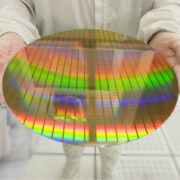 Hands holding a silicon wafers rainbow colours reflection light, working at clean room laboratory.