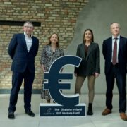 Two men and two women standing beside a Euro symbol.