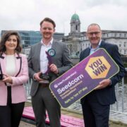 Woman and two men holding prizes.