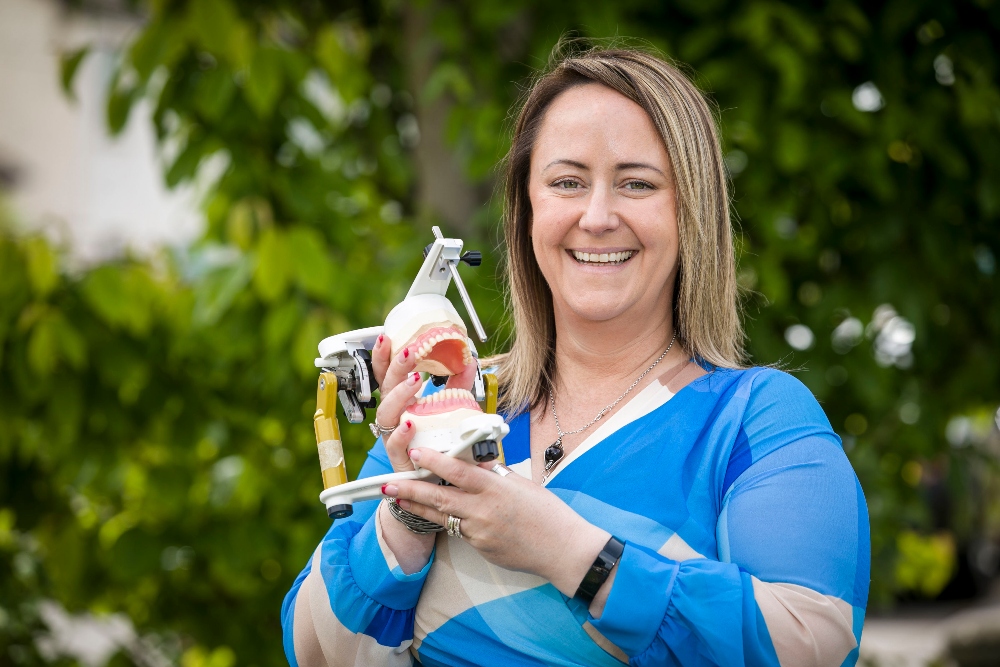 Woman holding dental prosthetics.