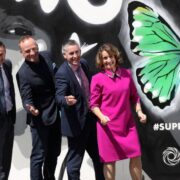Group of people in front of a mural with a green butterfly.