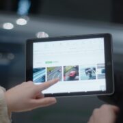 Woman looking at car models on iPad in car showroom.