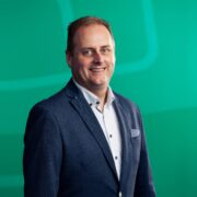 Man in suit in front of green background.