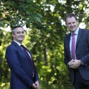 Two men in suits in a forest.