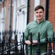 Man in green shirt standing outside a building.