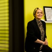 Smiling woman in dark suit.