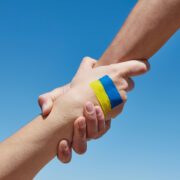 Helping hand to a person with flag of Ukraine.