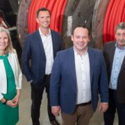 Woman in green dress with men in dark jackets.