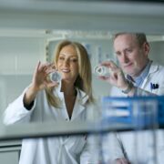 Woman and man in white coats holding grain samples.