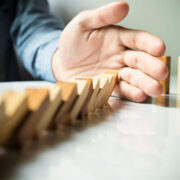 Hand stopping falling dominos.