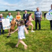 Children running in front of a group of people on a farm.