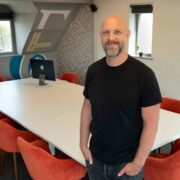 Man in black t-shirt in boardroom.