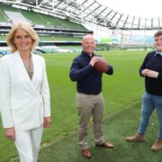 Woman in white business suit and two men at Aviva stadium in Dublin.