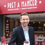 Man holding a coffee outside a Pret A Manger store.