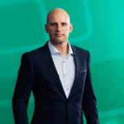 Man in suit in front of a green background.