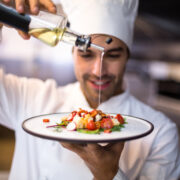 Chef putting oil on a dish.