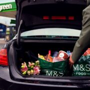 Person packing groceries into boot of a car at an Applegreen service station.