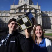 Scientists holding a satellite device.