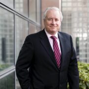 Man in dark suit with striped tie.