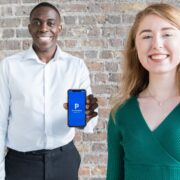 Man in white shirt holding smartphone and woman wearing green top.
