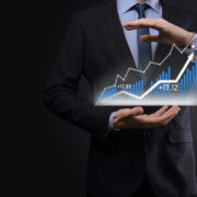 Businessman on a black background presses, presses a finger on a positive growth arrow.