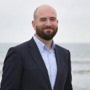 Man in navy blazer by the sea.