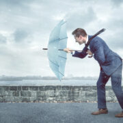Man holding umbrella walks into the wind.