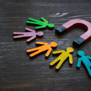 Magnet and figures of people indicating customer acquisition and retention.