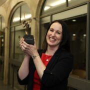 Woman in red dress holding a prize.