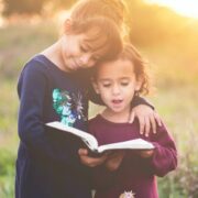 Young girls reading a book.