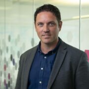 Dark-haired man in grey jacket.