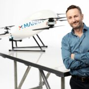 Man in blue shirt in front of a drone.