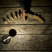 Hand stopping falling dominos.