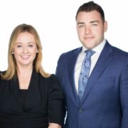 Woman in black dress beside man in blue suit.