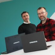 Two men behind laptops.