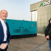 Two men in front of a gas-powered generator.